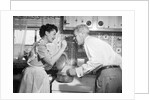 1950s housewife in kitchen having husband taste food on stove by Anonymous