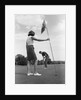 1970s couple playing golf man putting woman holding flag by Anonymous