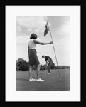 1970s couple playing golf man putting woman holding flag by Anonymous