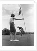 1970s couple playing golf man putting woman holding flag by Anonymous