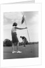 1970s couple playing golf man putting woman holding flag by Anonymous