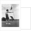 1970s couple playing golf man putting woman holding flag by Anonymous