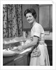 1960s woman housewife washing dishes in kitchen sink looking at camera by Anonymous
