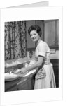 1960s woman housewife washing dishes in kitchen sink looking at camera by Anonymous