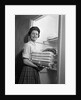 1950s 1960s housewife holding laundry folded towels by linen closet looking at camera by Anonymous