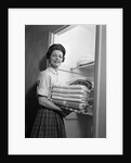 1950s 1960s housewife holding laundry folded towels by linen closet looking at camera by Anonymous