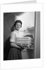 1950s 1960s housewife holding laundry folded towels by linen closet looking at camera by Anonymous