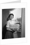 1950s 1960s housewife holding laundry folded towels by linen closet looking at camera by Anonymous