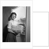 1950s 1960s housewife holding laundry folded towels by linen closet looking at camera by Anonymous