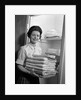 1960s woman holding laundry folded towels by linen closet looking at camera by Anonymous
