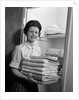 1960s woman holding laundry folded towels by linen closet looking at camera by Anonymous