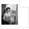 1960s woman holding laundry folded towels by linen closet looking at camera by Anonymous