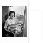 1960s woman holding laundry folded towels by linen closet looking at camera by Anonymous