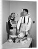 1950s satisfied amused smiling couple husband wife in kitchen cooking together by Anonymous