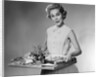 1950s woman looking at camera smiling holding platter of hors d'oeuvres snacks by Anonymous