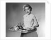 1950s woman looking at camera smiling holding platter of hors d'oeuvres snacks by Anonymous