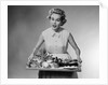 1950s woman looking at camera speaking holding platter of hors d'oeuvres snacks by Anonymous