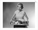 1950s woman looking at camera speaking holding platter of hors d'oeuvres snacks by Anonymous