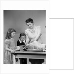 1940s mother son daughter in kitchen stuffing turkey for thanksgiving dinner by Anonymous