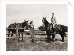 1930s 1940s couple in riding gear man riding horse woman standing by wooden fence by Anonymous