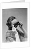 1930s 1940s woman putting on taking off black eye mask by Anonymous