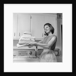 1960s satisfied woman homemaker holding folded laundry by Anonymous