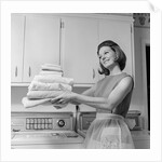 1960s satisfied woman homemaker holding folded laundry by Anonymous