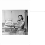 1960s satisfied woman homemaker holding folded laundry by Anonymous