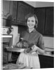 1960s smiling woman in kitchen taking roast out of oven looking at camera by Anonymous