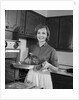 1960s smiling woman in kitchen taking roast out of oven looking at camera by Anonymous