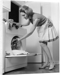 1970s woman removing laundry from dryer by Anonymous