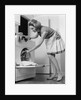 1970s woman removing laundry from dryer by Anonymous