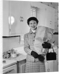 1950s smiling woman in kitchen holding grocery bag handbag wearing hat gloves looking at camera by Anonymous