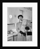 1950s smiling woman in kitchen holding grocery bag handbag wearing hat gloves looking at camera by Anonymous