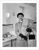 1950s smiling woman in kitchen holding grocery bag handbag wearing hat gloves looking at camera by Anonymous