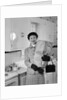 1950s smiling woman in kitchen holding grocery bag handbag wearing hat gloves looking at camera by Anonymous