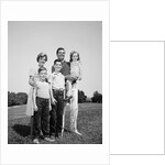 1960s smiling family portrait standing on grass mother father three children by Anonymous