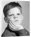 1960s little boy making angry funny facial expression looking at camera by Anonymous