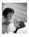 1960s daughter with mother tucking into bed by Anonymous