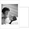1960s daughter with mother tucking into bed by Anonymous