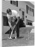 1960s father and young daughter playing croquet in yard by Anonymous