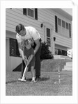 1960s father and young daughter playing croquet in yard by Anonymous