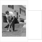 1960s father and young daughter playing croquet in yard by Anonymous