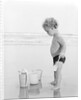 1960s 1970s child toddler standing in sand water bucket shovel by Anonymous