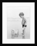 1960s 1970s child toddler standing in sand water bucket shovel by Anonymous