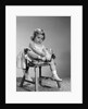 1960s little girl putting on shoes sitting on chair by Anonymous
