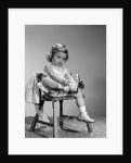 1960s little girl putting on shoes sitting on chair by Anonymous