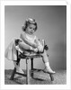 1960s little girl putting on shoes sitting on chair by Anonymous