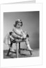 1960s little girl putting on shoes sitting on chair by Anonymous