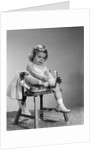 1960s little girl putting on shoes sitting on chair by Anonymous